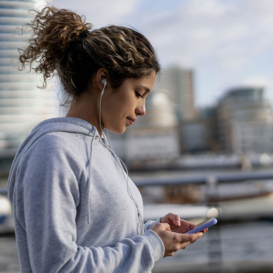 A woman tracks her exercise data on her smart phone while running outside
