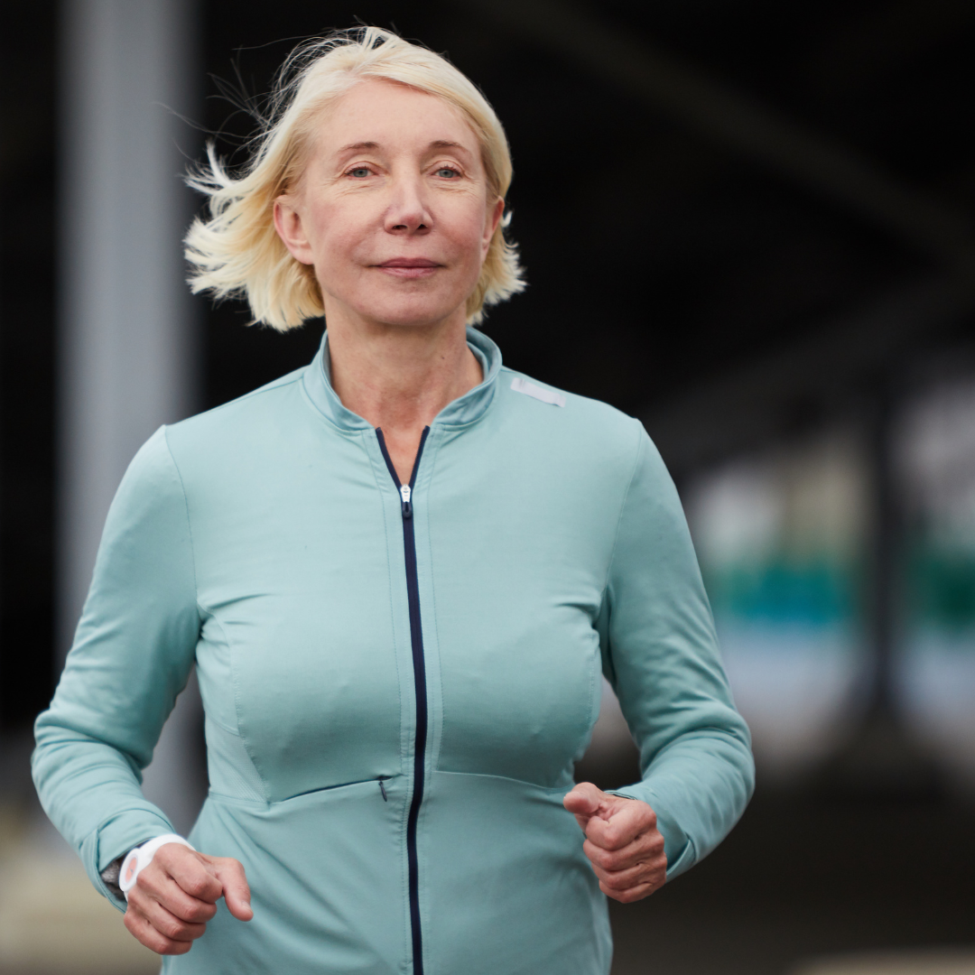 a older woman is shown jogging outside in a light blue half-zip