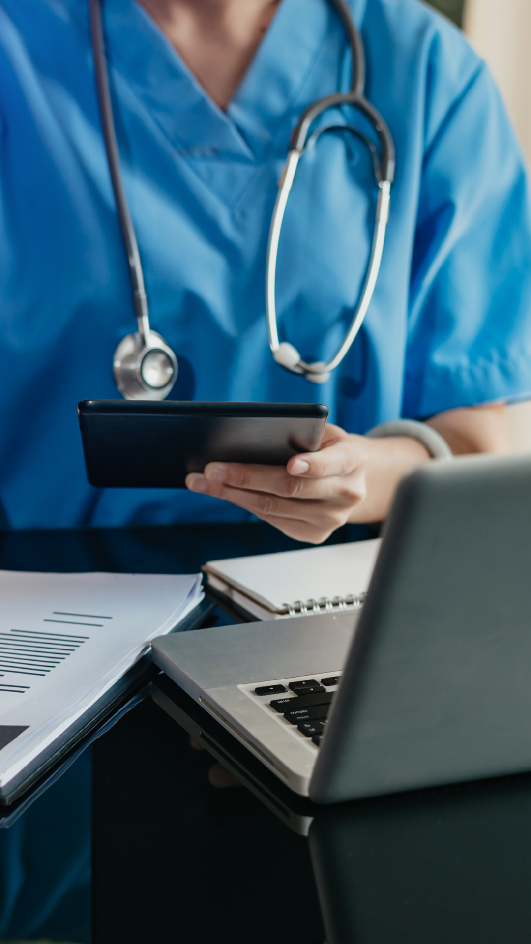A doctor or nurse fills out paperwork at their desk